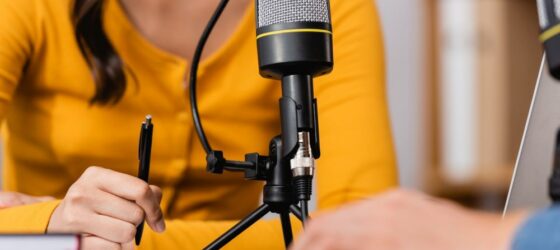 woman in yellow shirt with microphone in front of her. concept of podcasting