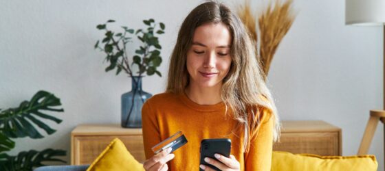 Happy woman shopping online with credit card and cell phone at home